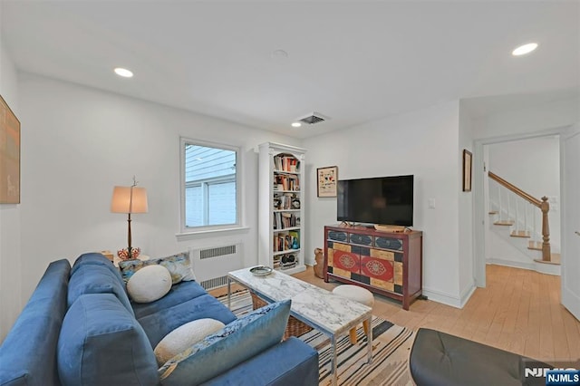 living area with recessed lighting, radiator, visible vents, light wood-style flooring, and stairs