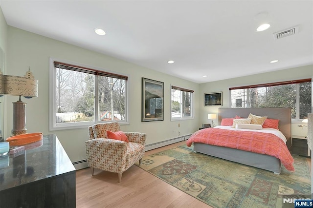 bedroom with light wood finished floors, a baseboard radiator, visible vents, and recessed lighting