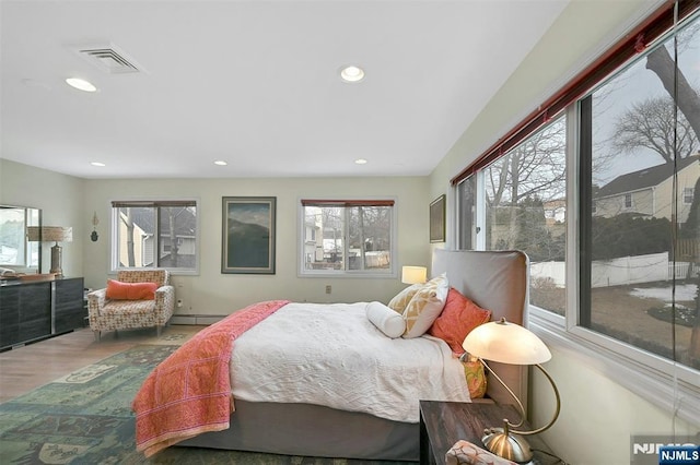 bedroom featuring visible vents, a baseboard heating unit, wood finished floors, and recessed lighting