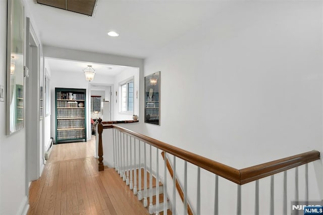 corridor featuring visible vents, light wood finished floors, and an upstairs landing