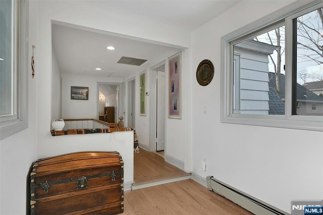 hallway featuring light wood finished floors, recessed lighting, a baseboard heating unit, attic access, and baseboards