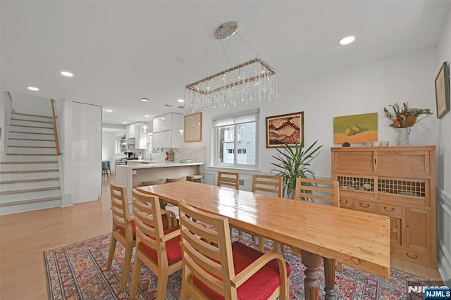 dining area featuring recessed lighting, light wood finished floors, and stairs