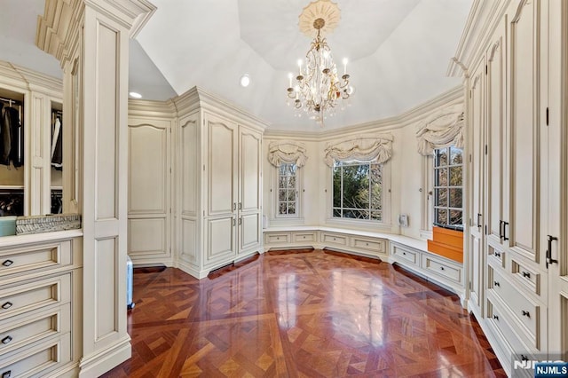 walk in closet with lofted ceiling, an inviting chandelier, and dark parquet floors