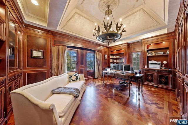 office area featuring built in shelves, dark parquet flooring, a chandelier, crown molding, and wood walls