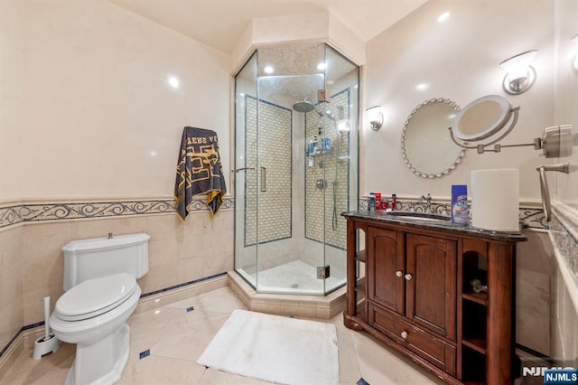 bathroom with tile walls, vanity, an enclosed shower, and toilet