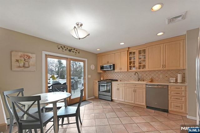 kitchen with stainless steel appliances, tasteful backsplash, light countertops, visible vents, and glass insert cabinets