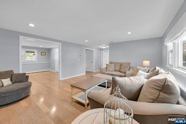 living room with light wood finished floors, baseboard heating, recessed lighting, and baseboards