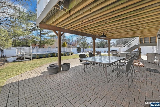 view of patio featuring stairway, outdoor dining area, and fence