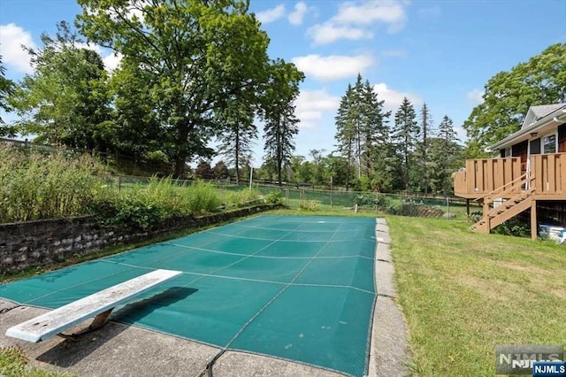 view of pool featuring a lawn and a diving board