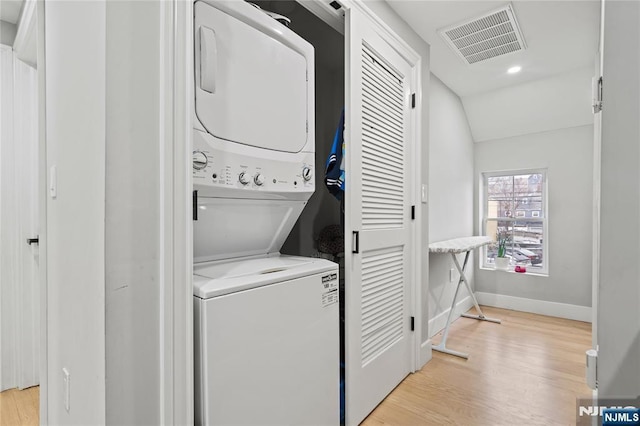 laundry area featuring light wood-type flooring and stacked washer / dryer