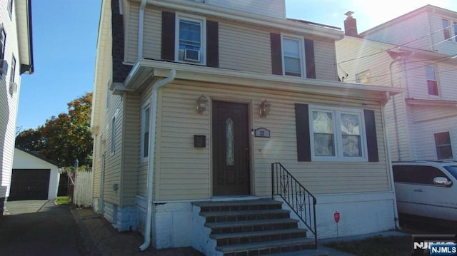 american foursquare style home with a garage, entry steps, and an outdoor structure