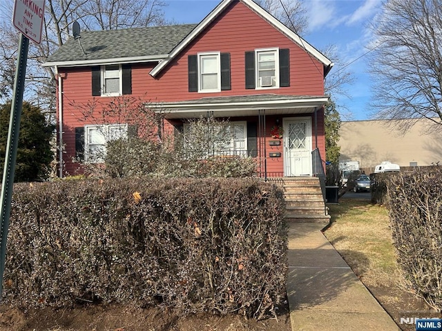 traditional-style home featuring a shingled roof and fence