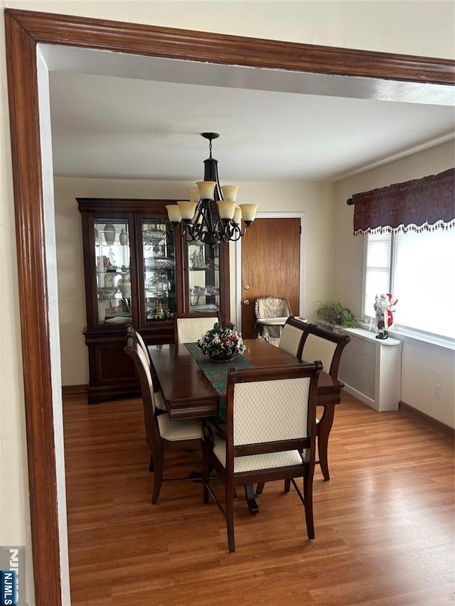 dining area with a notable chandelier, baseboards, and wood finished floors