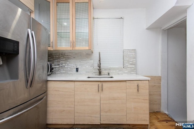 kitchen featuring decorative backsplash, sink, light brown cabinetry, and stainless steel fridge with ice dispenser