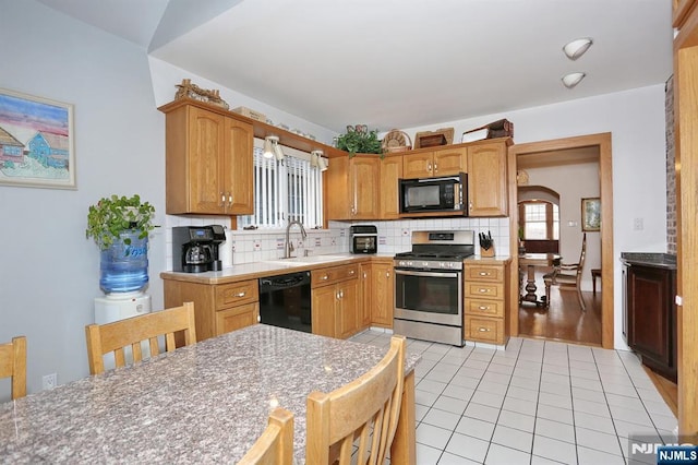 kitchen featuring black appliances, tasteful backsplash, light countertops, and a sink