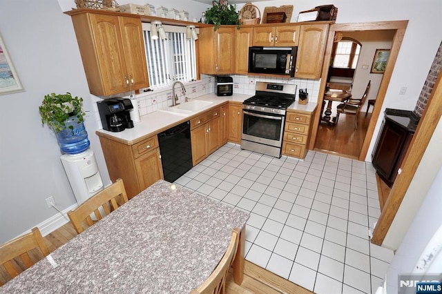 kitchen with black appliances, backsplash, light countertops, and a sink