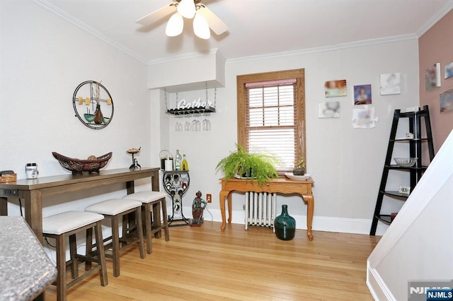 dining area featuring light wood-style flooring, baseboards, radiator heating unit, and crown molding