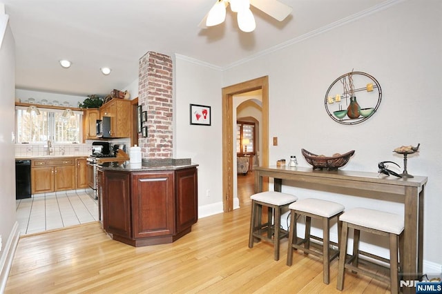 kitchen featuring arched walkways, backsplash, dishwasher, light wood finished floors, and gas stove