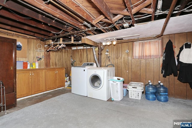 laundry room with cabinet space, wood walls, and washing machine and clothes dryer