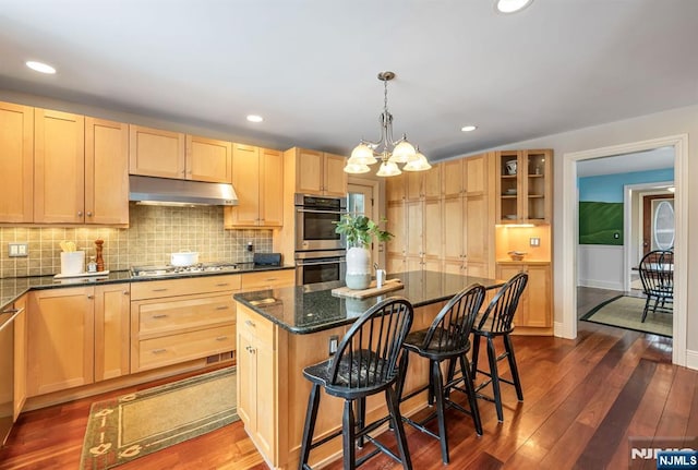 kitchen featuring dark wood-style flooring, light brown cabinetry, appliances with stainless steel finishes, a kitchen island, and under cabinet range hood