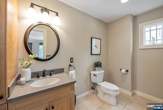 bathroom with toilet, tile patterned flooring, baseboards, and vanity