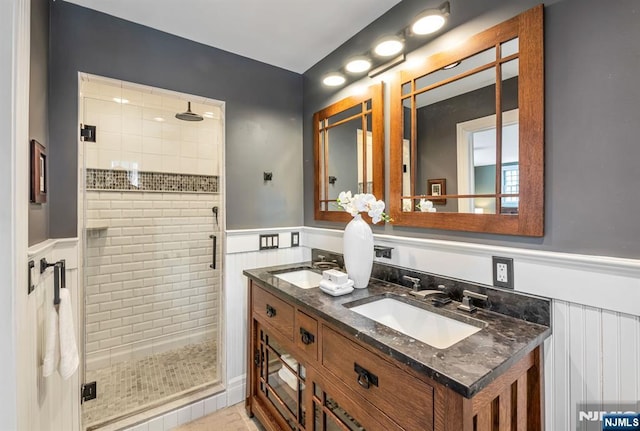 full bathroom featuring a wainscoted wall, a shower stall, and a sink