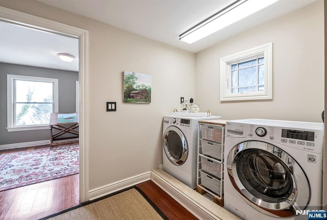 clothes washing area featuring dark wood-style floors, laundry area, washing machine and dryer, and baseboards