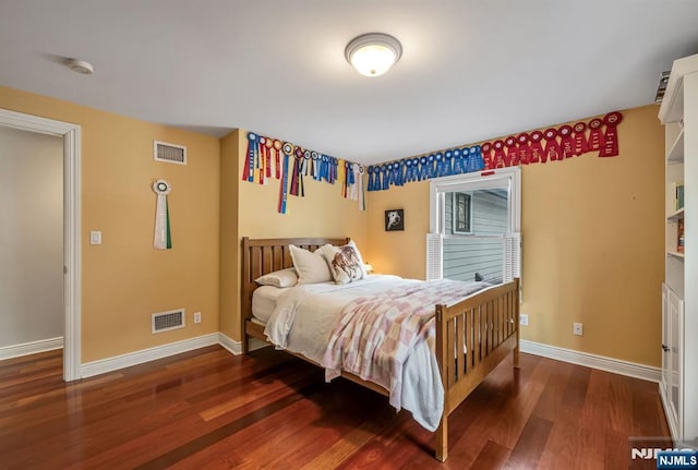 bedroom featuring baseboards, visible vents, and wood finished floors