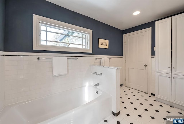 full bath with a wainscoted wall, tile walls, and a bath