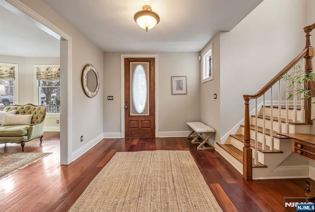 entrance foyer featuring dark wood-style floors, a healthy amount of sunlight, baseboards, and stairs