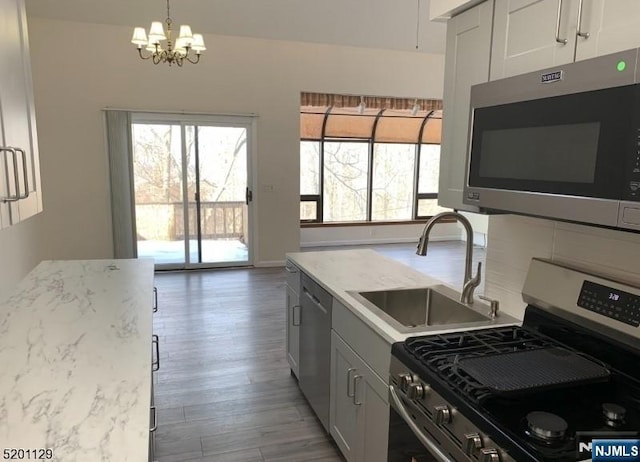 kitchen with appliances with stainless steel finishes, sink, pendant lighting, and white cabinetry