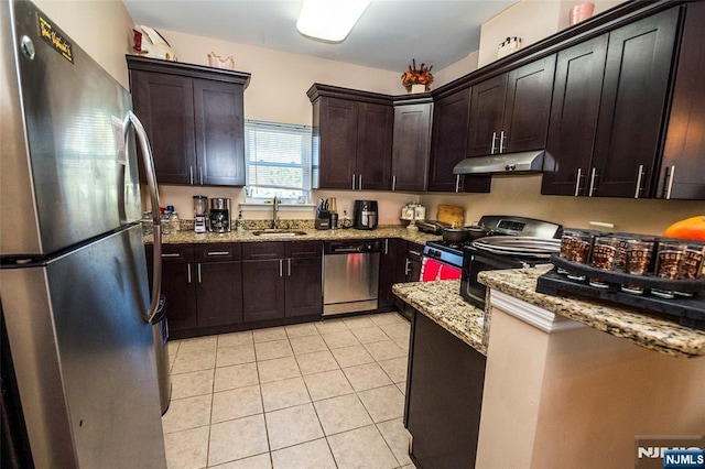 kitchen with stainless steel appliances, dark brown cabinetry, light stone countertops, sink, and light tile patterned flooring