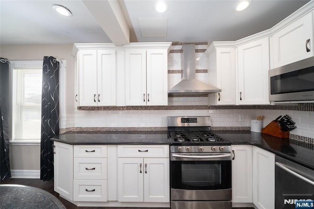 kitchen with wall chimney exhaust hood, stainless steel appliances, white cabinets, and backsplash