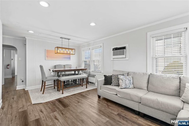 dining space with radiator heating unit, hardwood / wood-style flooring, crown molding, and a wall unit AC