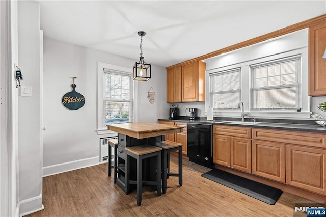 kitchen featuring a center island, light hardwood / wood-style flooring, black dishwasher, sink, and a kitchen breakfast bar