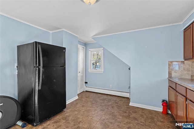 kitchen featuring crown molding, a baseboard heating unit, black fridge, and tasteful backsplash