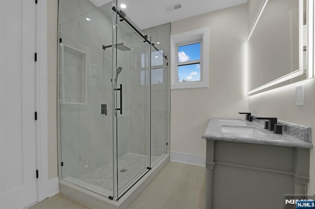 bathroom featuring a shower with shower door and vanity