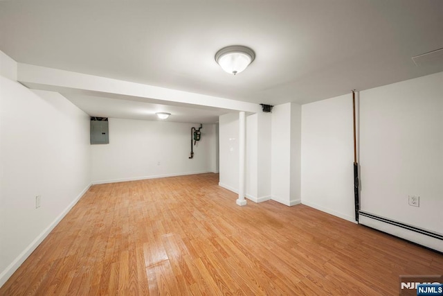 basement featuring light wood-type flooring, electric panel, and a baseboard radiator