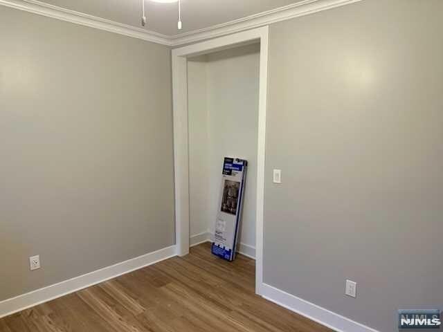 unfurnished room with ornamental molding, dark wood finished floors, and baseboards