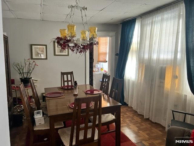 dining space featuring a notable chandelier and a drop ceiling