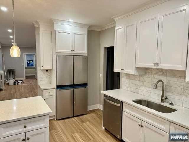 kitchen with light wood-type flooring, a sink, stainless steel appliances, and light countertops