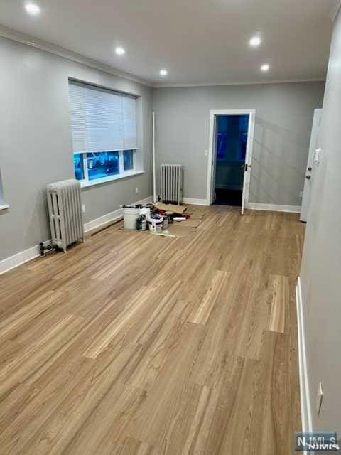 interior space featuring baseboards, radiator heating unit, wood finished floors, and recessed lighting