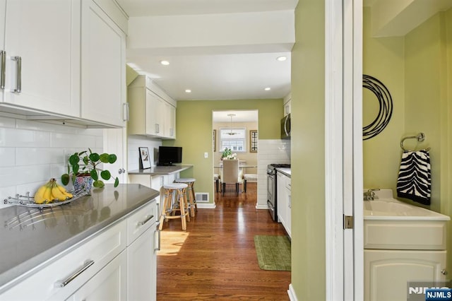 kitchen with dark wood-style flooring, stainless steel appliances, recessed lighting, tasteful backsplash, and white cabinets