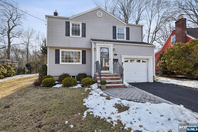 view of front of house featuring a garage, aphalt driveway, and a chimney