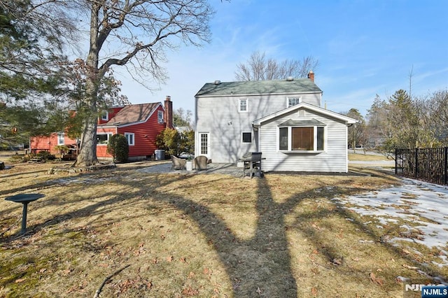 back of property with central AC unit, fence, a lawn, a chimney, and a patio area