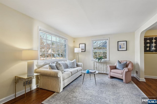 living room with dark wood-style floors, visible vents, and baseboards