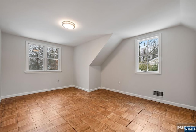 additional living space with lofted ceiling, baseboards, and visible vents