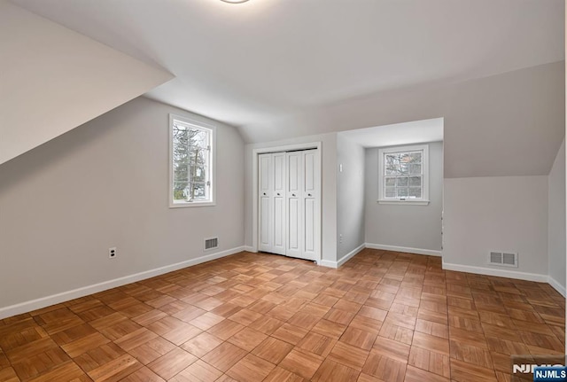 additional living space featuring plenty of natural light, baseboards, and visible vents