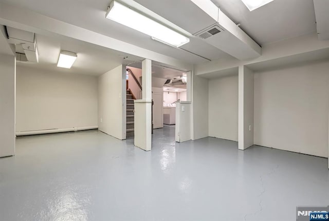 finished basement featuring washer / dryer, a baseboard radiator, stairs, and visible vents