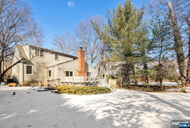 snow covered property with a deck and a chimney